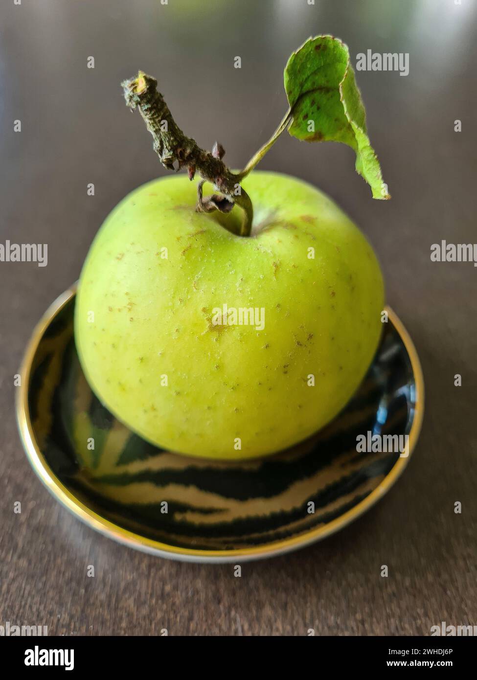 A whole green round apple with stem and leaf Stock Photo