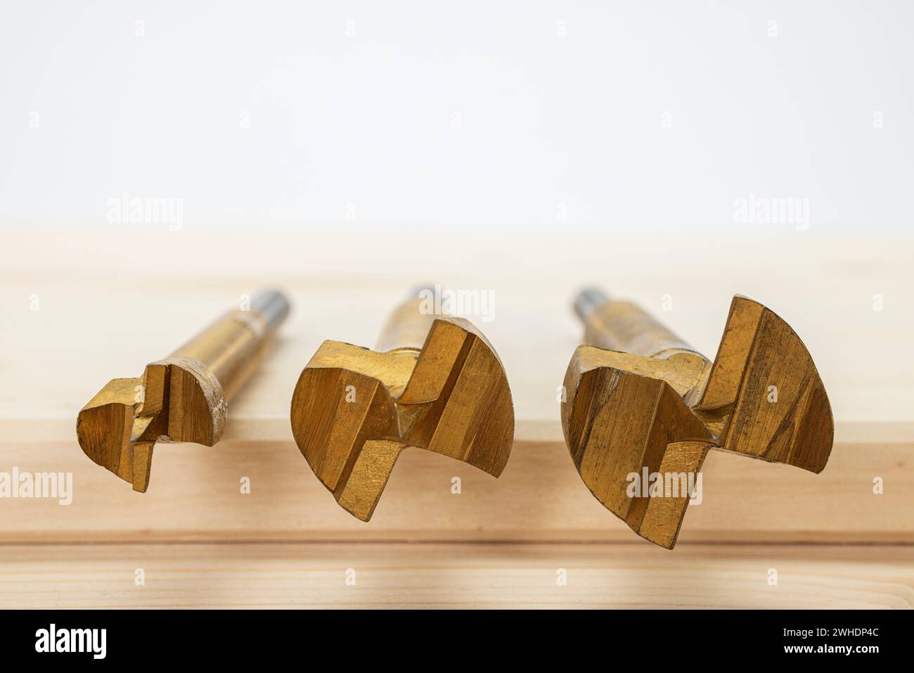 Woodworking, three Forstner bits 15, 25, and 30 mm, lying on glued wood panel, blurring, Stock Photo