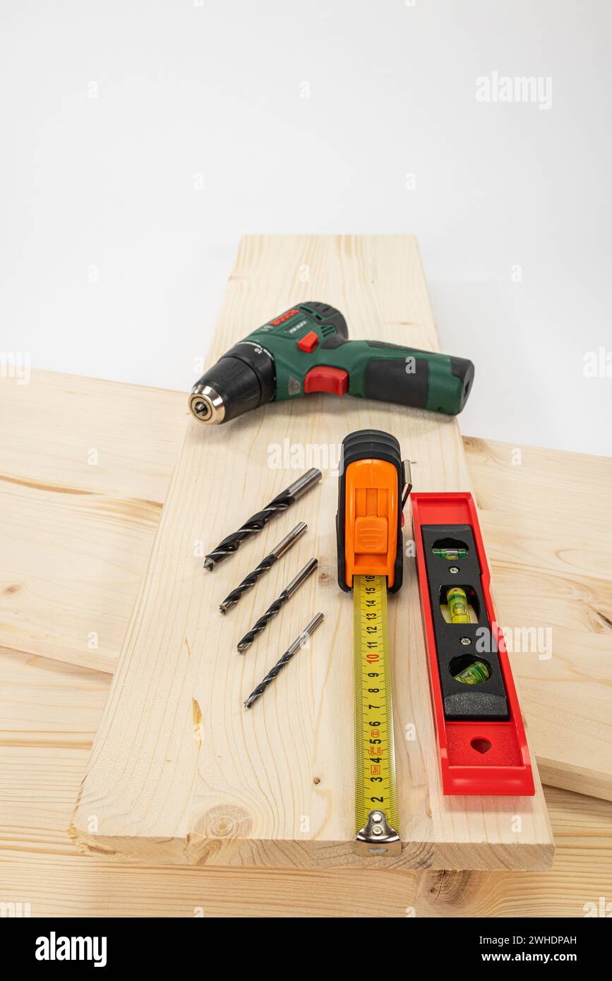 Measure glued wood panel, yellow measuring tape, wood drill, cordless drill, water wagon, white background, Stock Photo