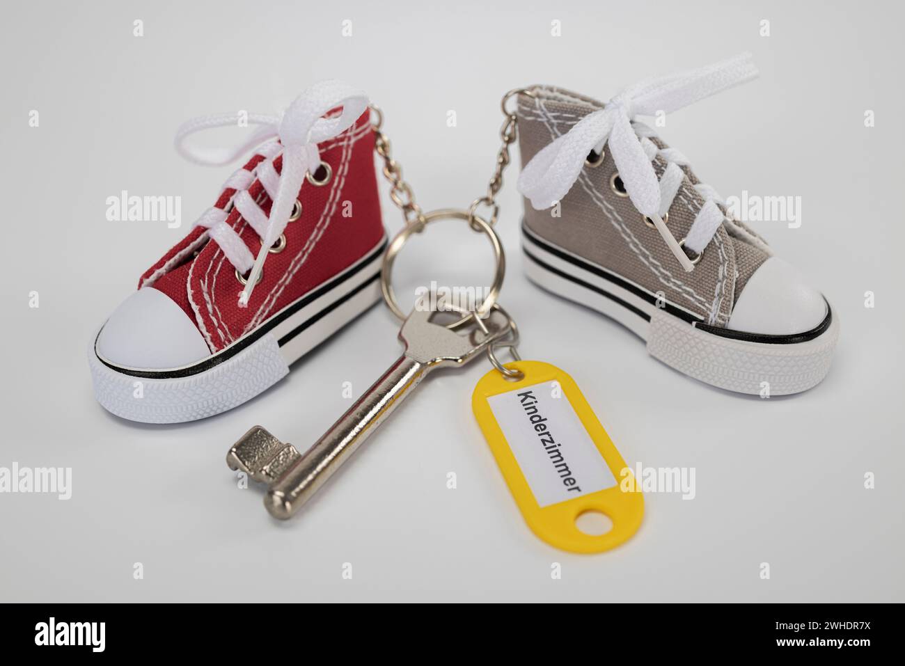 Room key with yellow keychain, labeled ëchildren's roomë, two sneakers keychain, miniature sneakers, colorful keychain, white background, Stock Photo