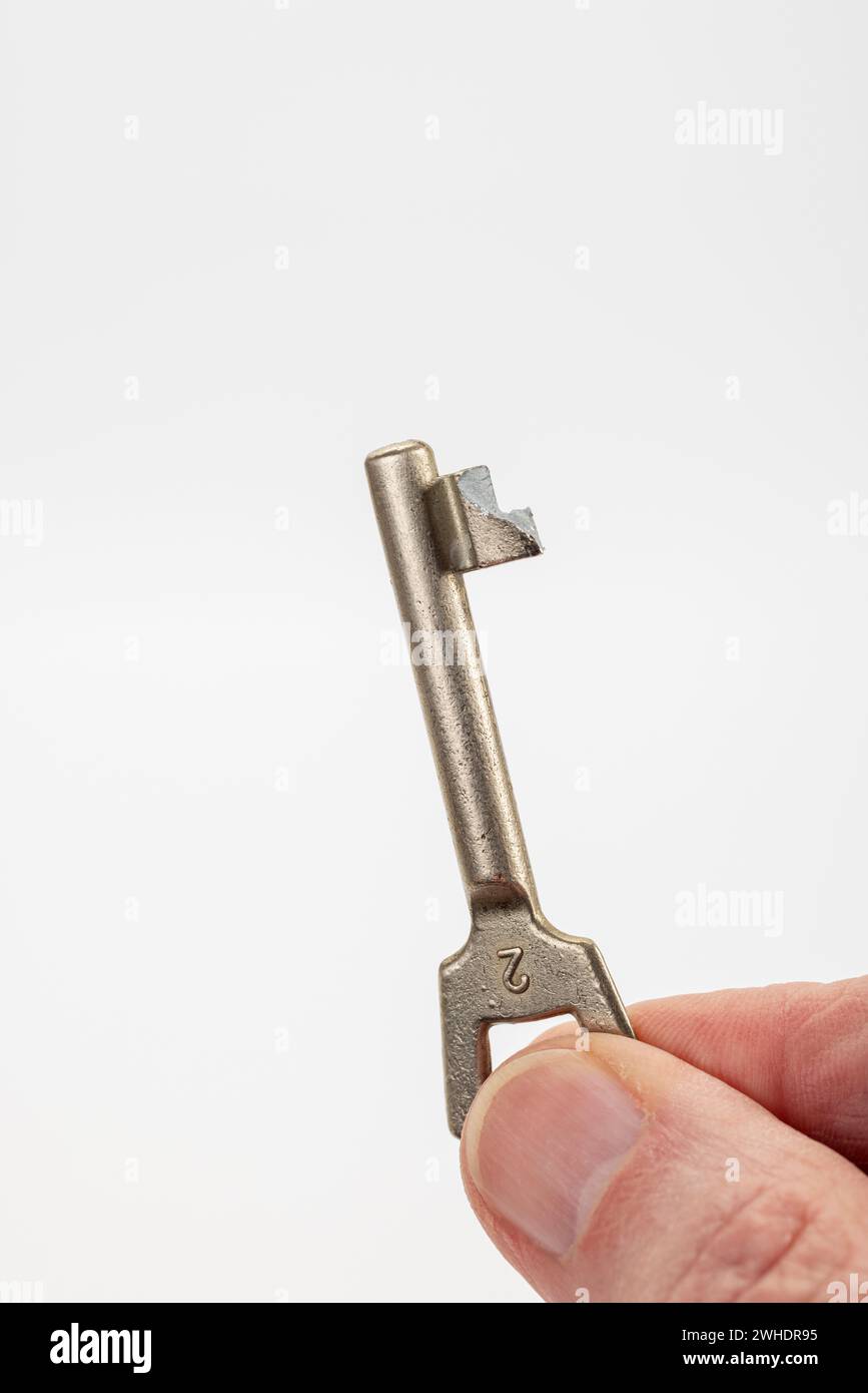 Male hand holding a broken door key, colored bar key, white background, Stock Photo