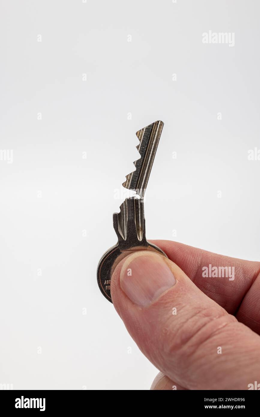 Male hand holding an open door key, cylinder key, white background, Stock Photo