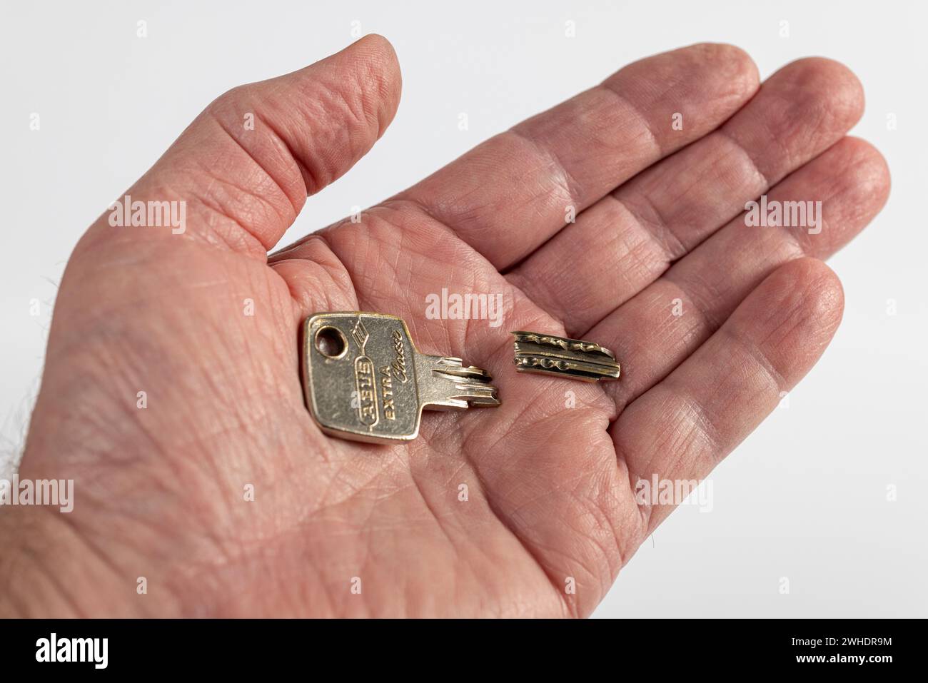 Broken apartment key on man's palm, dimple key, cylinder key, white background, Stock Photo