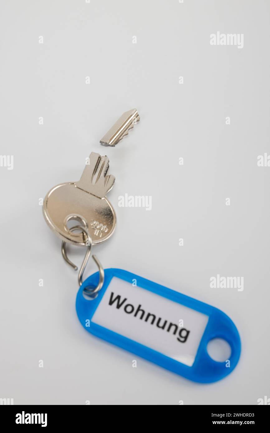 Broken apartment key with blue key fob, inscription 'Wohnung', white background, Stock Photo