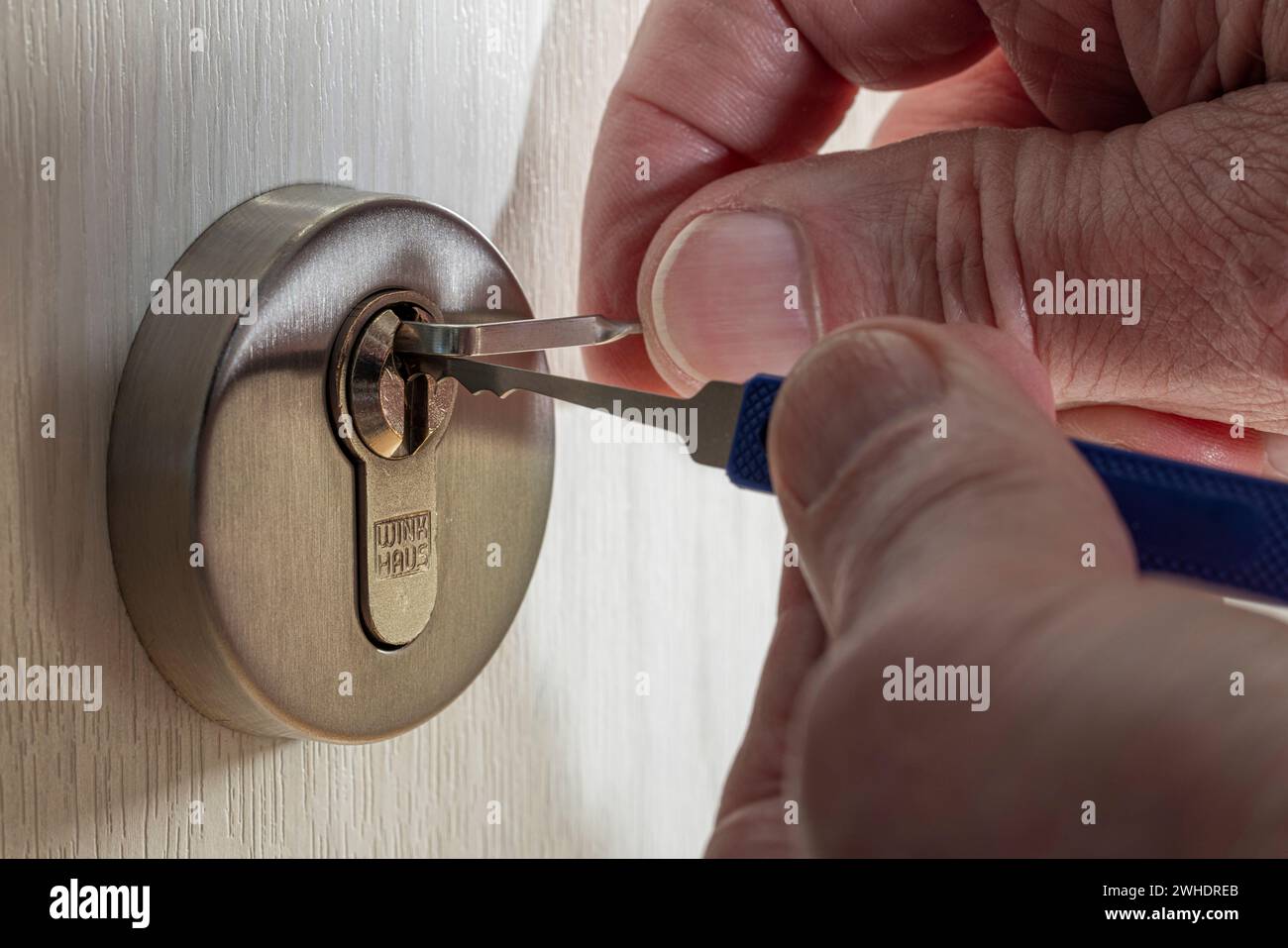 Open cylinder lock with lockpicking tool, man's hand, detail, symbolic