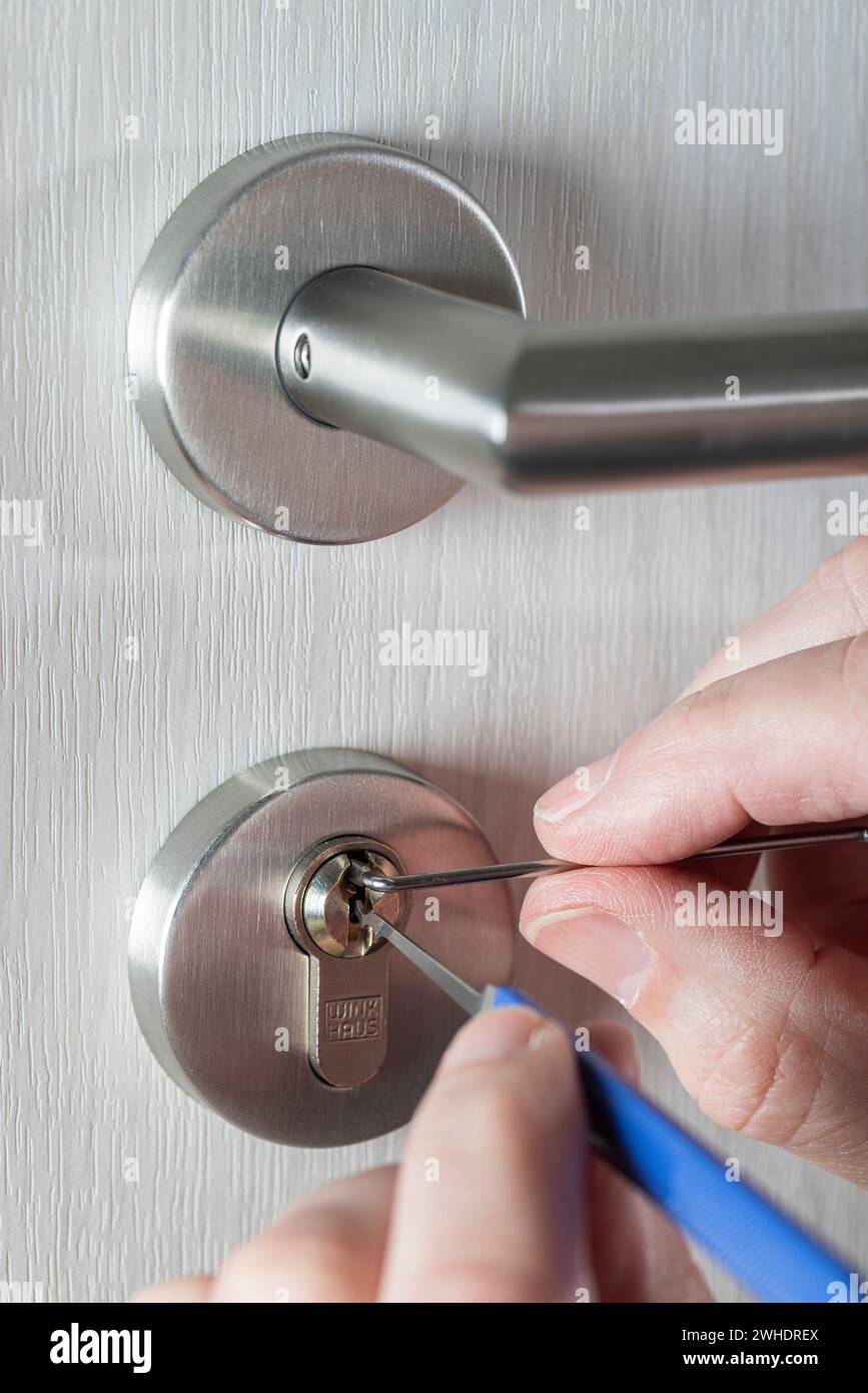 Open cylinder lock with lockpicking tool, man's hand, detail, symbolic