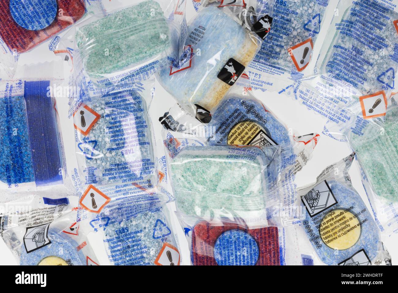 Many dishwasher detergent tabs in foil packaging with hazard pictogram