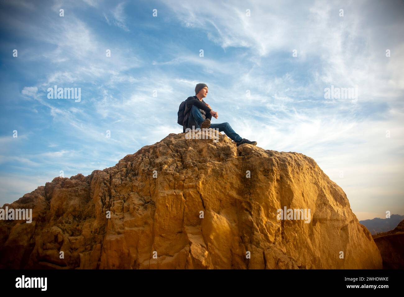 male hiker resting on top of rocks looking at the view, getting away from it all. Stock Photo