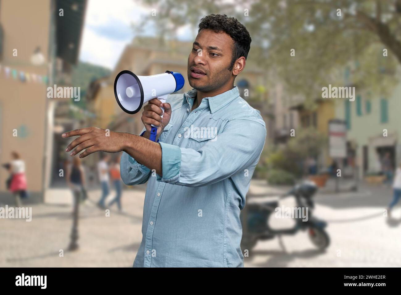 Young man with megaphone standing on blur city street background ...