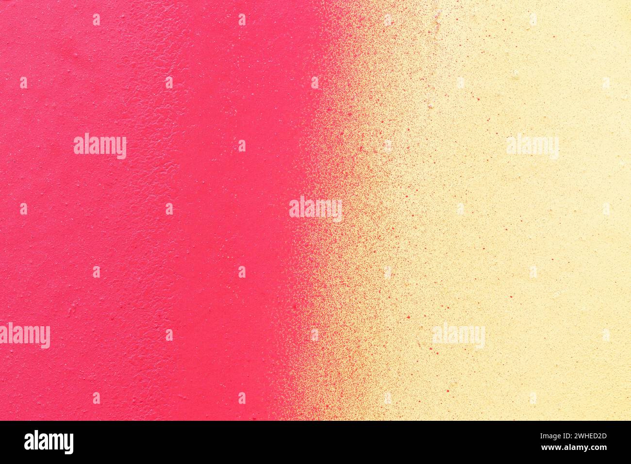 Macro close-up of a wall spray painted with pink and yellow. Abstract full frame textured splattered graffiti background with copy space. Stock Photo