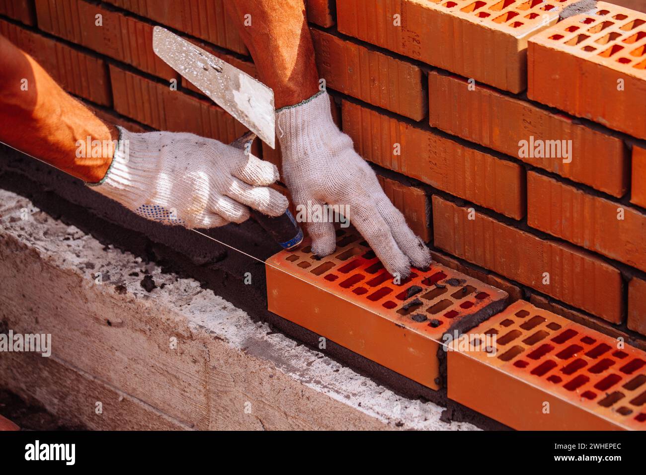 Builder laying bricks on construction site. Stock Photo