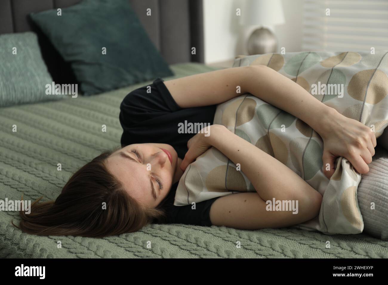 Sad young woman lying on bed at home Stock Photo - Alamy