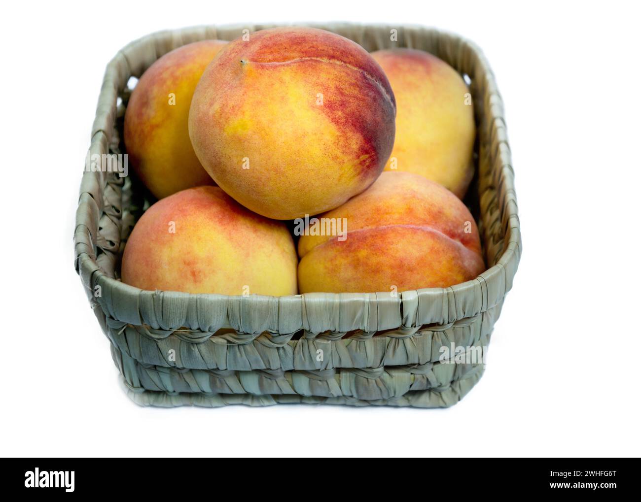 Basket full of fresh from the garden organic yellow peaches on a white background Stock Photo