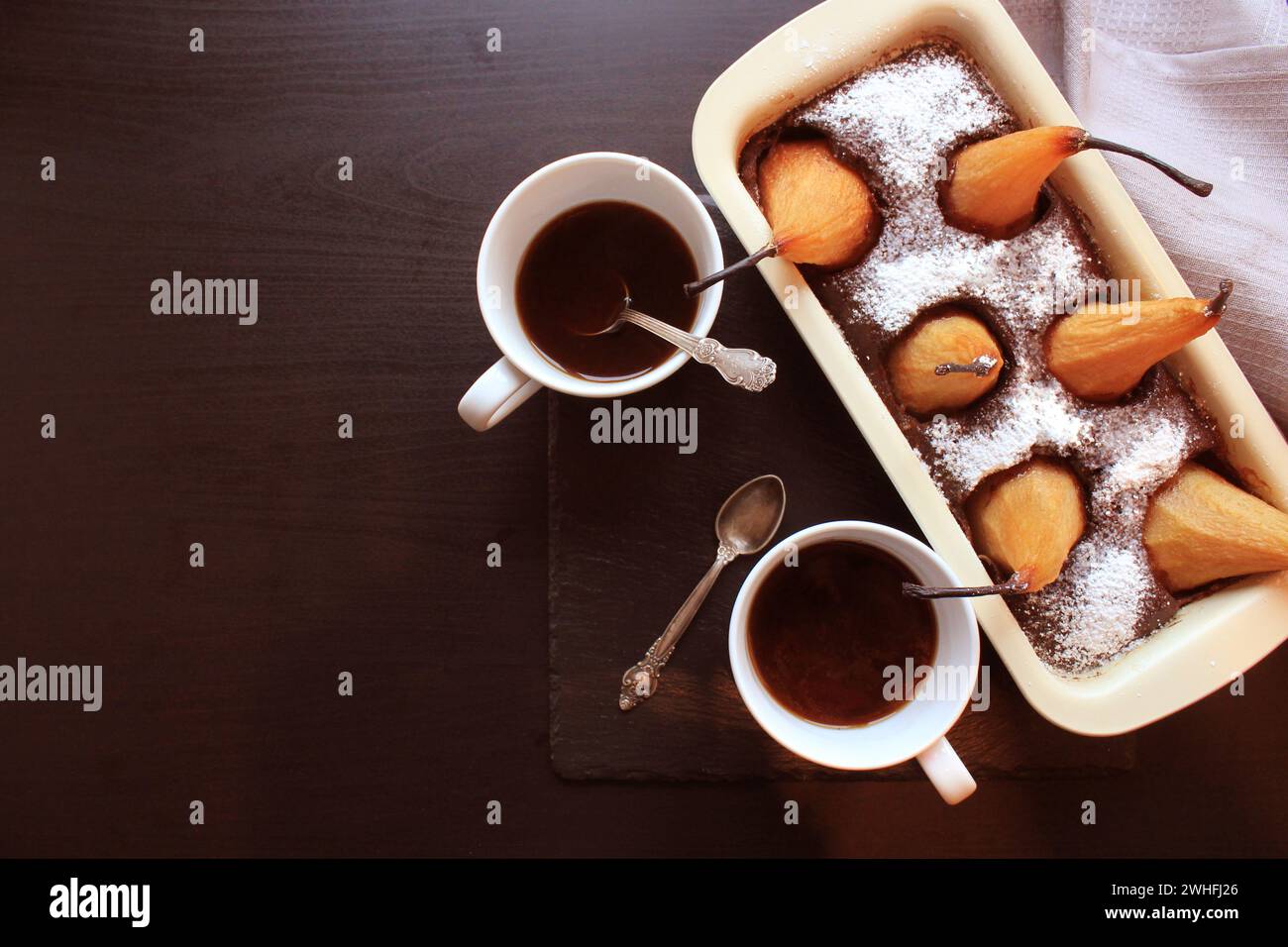 Chocolate loaf cake with whole pears baked inside and two cups coffee ...