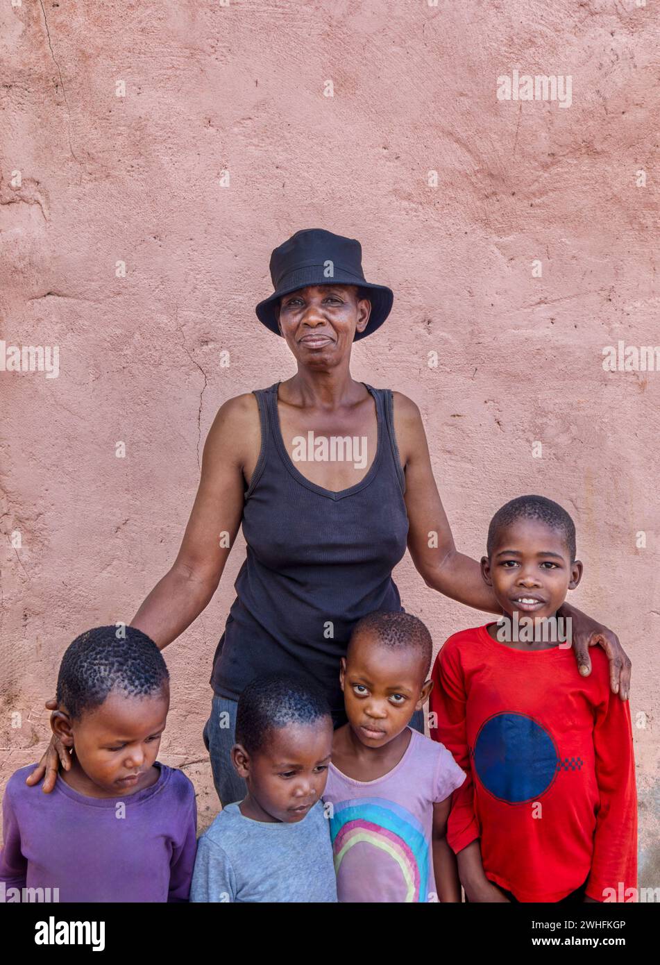 village african kids and the mother posing in front of a pink wall , late afternoon Stock Photo