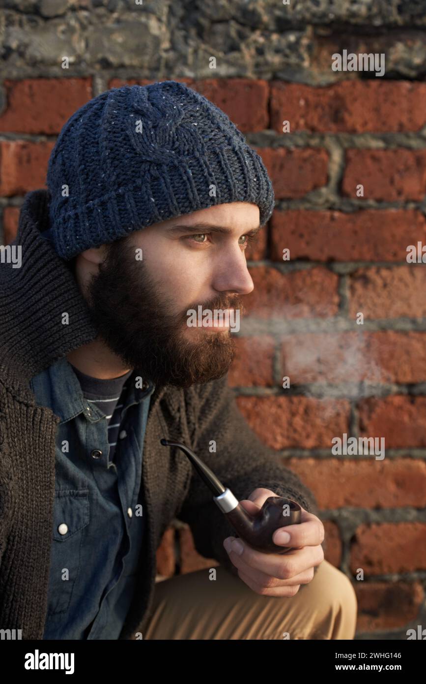 Face, winter and pipe smoke with man outdoor on wall background for fashion, style or clothing. Morning, tobacco or habit and young person with beanie Stock Photo