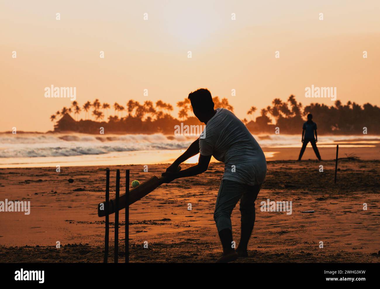Boy playing cricket at sunset on tropical beach in Sri Lanka Stock Photo