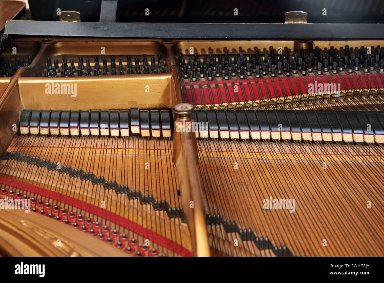 Inside a grand piano with metal frame, strings, hammer and damper, view into the mechanics of an older acoustic musical instrume Stock Photo