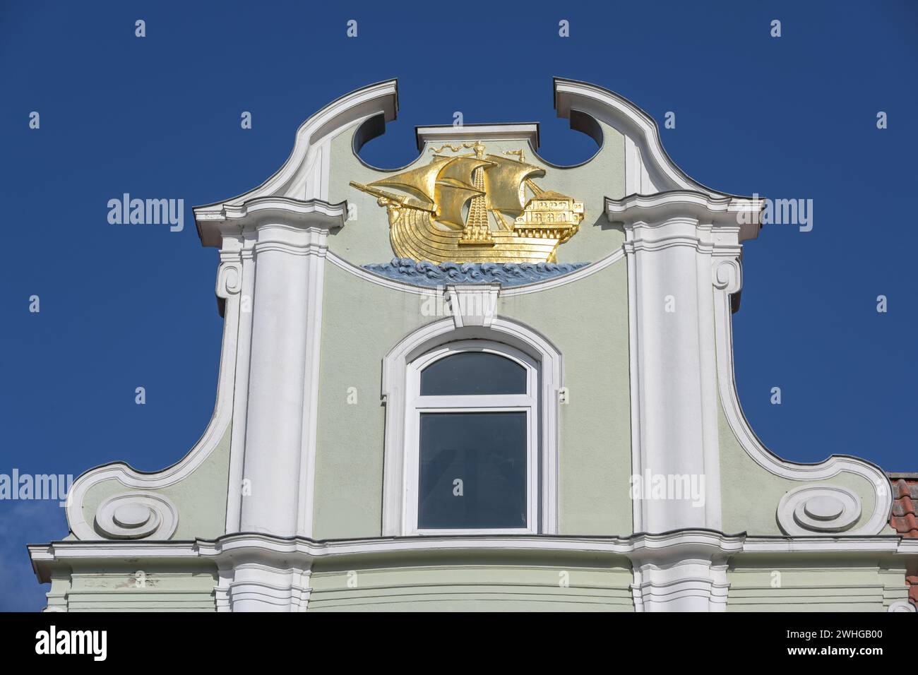 Golden sailing ship on the gable of a merchant house in the historic old town of the hanseatic city of Lubeck in Germany, blue s Stock Photo