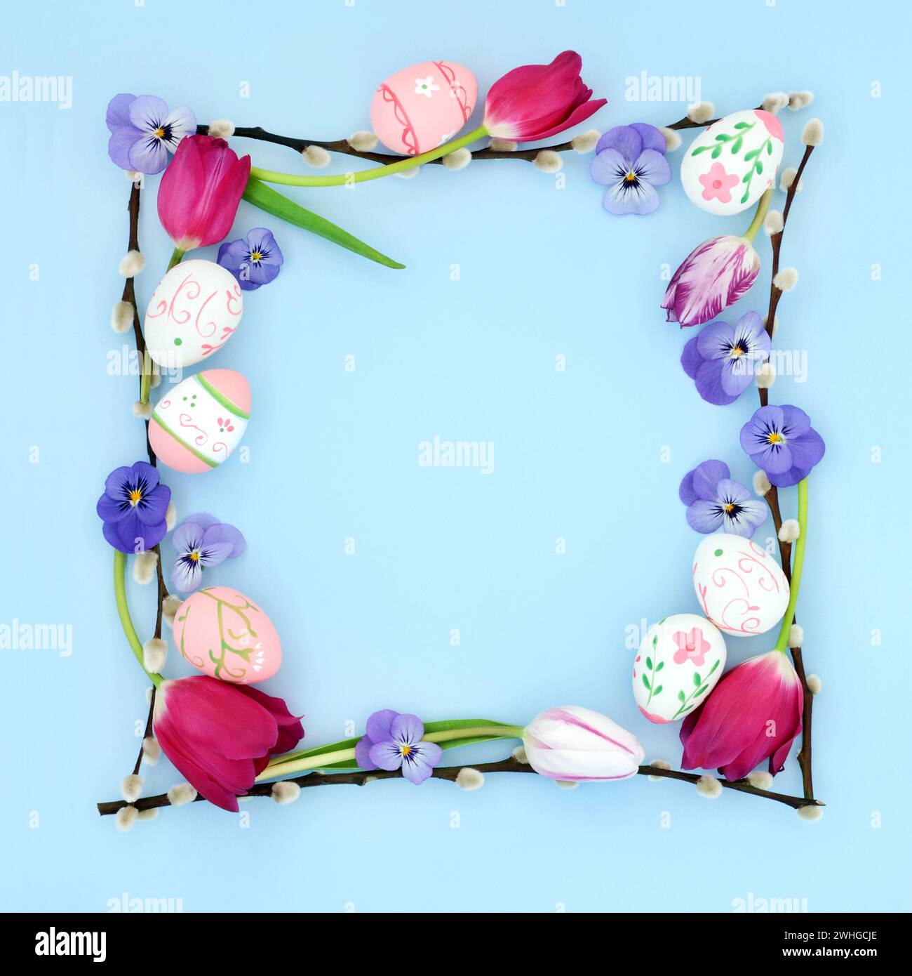 Abstract Easter background border with decorative eggs, flowers and willow branches on pastel blue. Minimal natural fun nature birder frame. Stock Photo