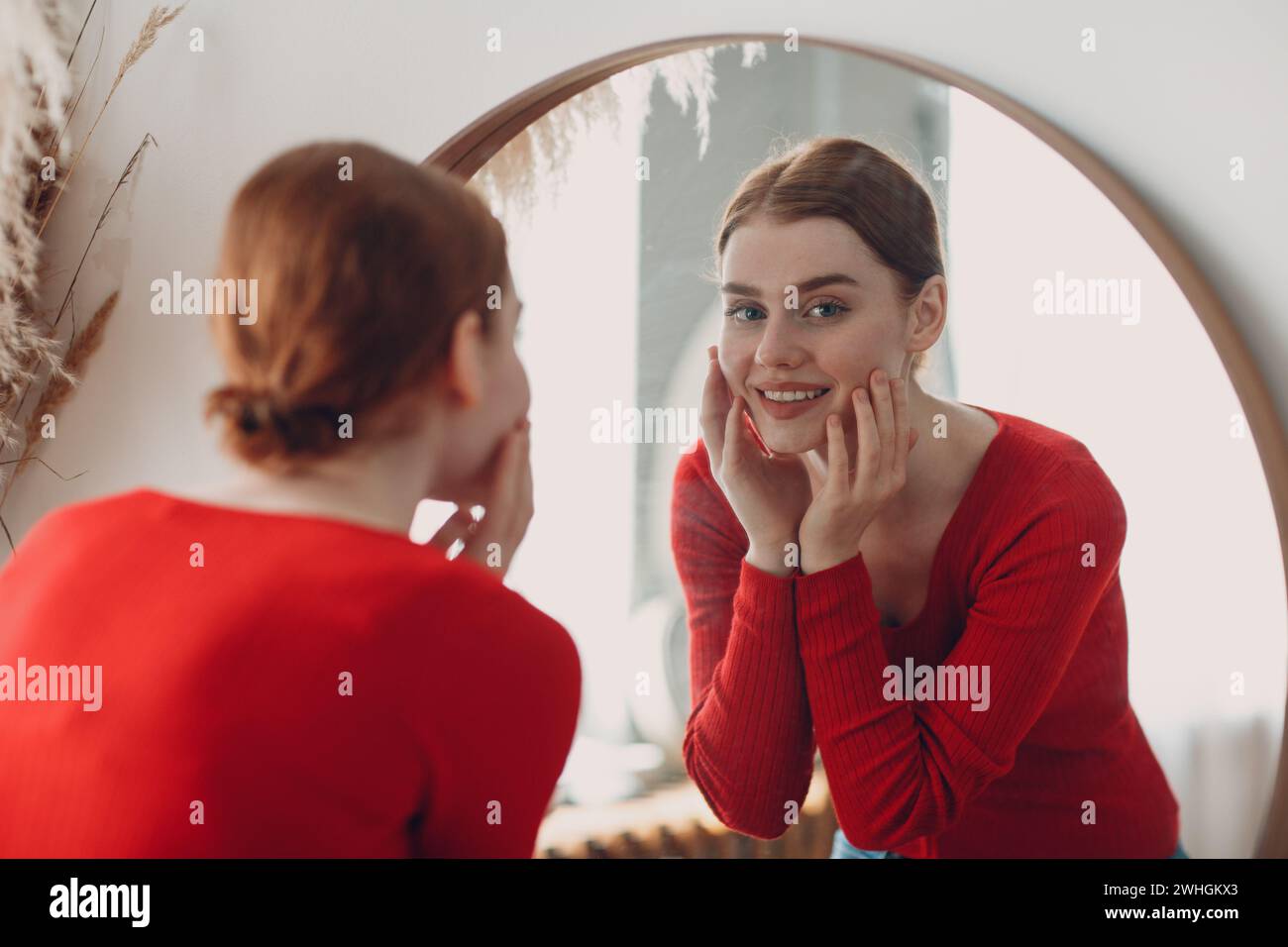 Young beautiful woman standing front of mirror in living room Stock Photo