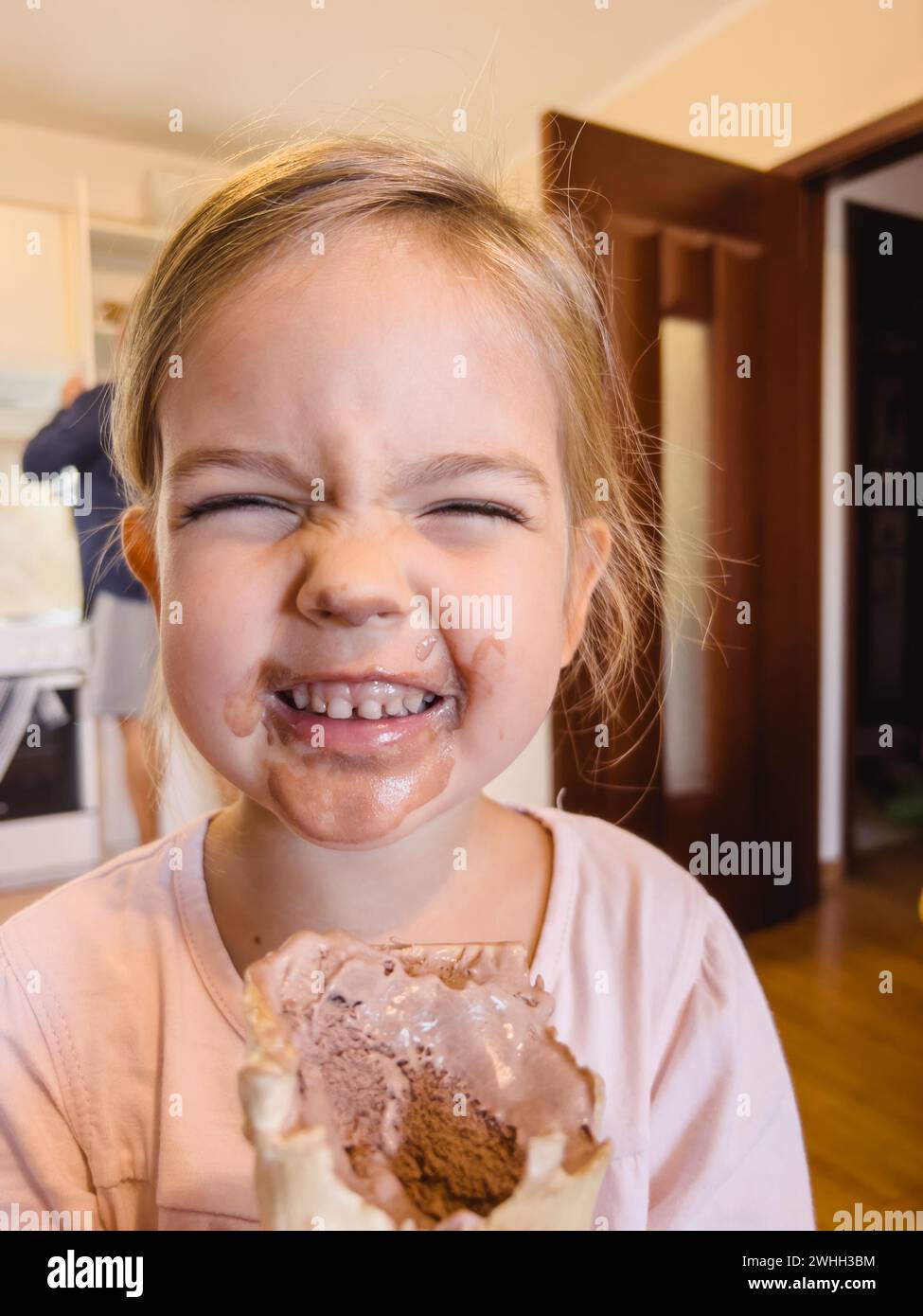 Little smiling girl with a dirty face holds chocolate ice cream in a waffle cup Stock Photo