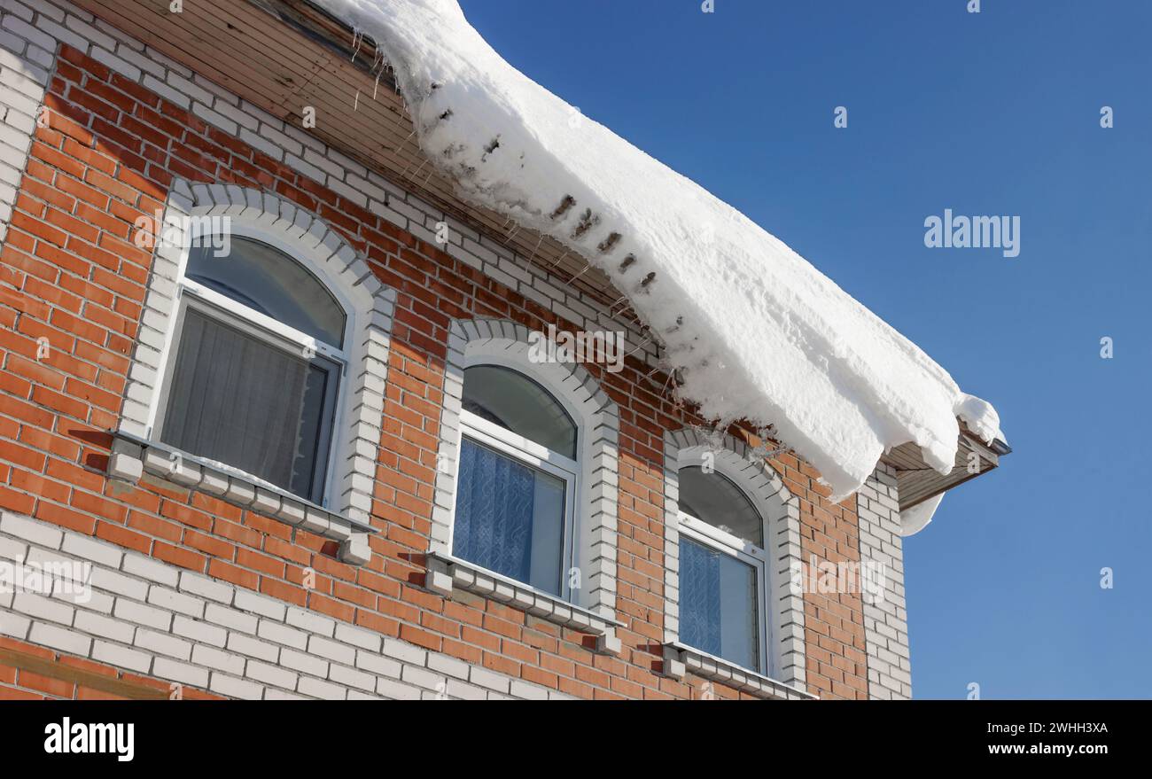 Threat of snow falling from roof. Photo was taken in middle of winter. Increased danger Stock Photo