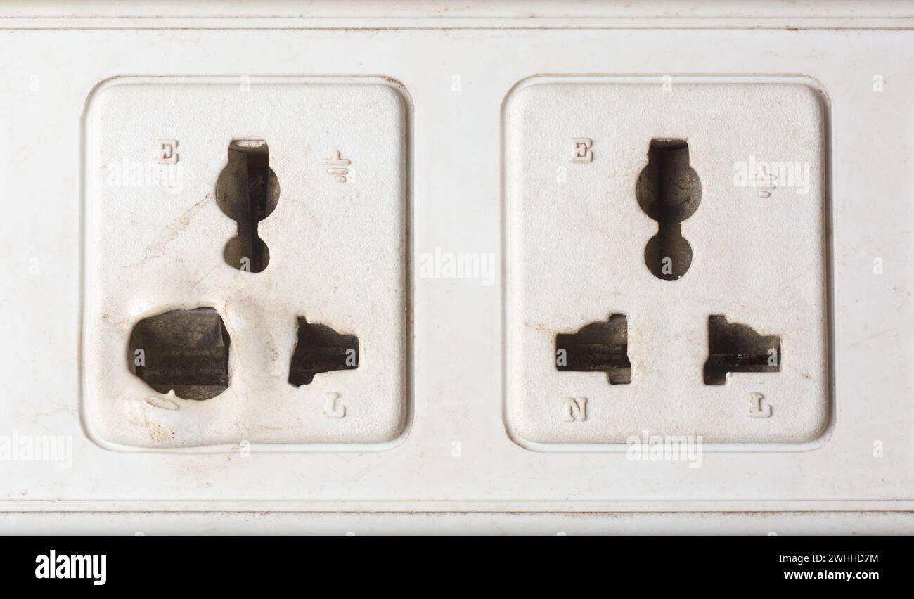 close-up of old electrical power sockets with melted and deformed plastic around the socket openings, overheated due to loose connections, overloaded Stock Photo