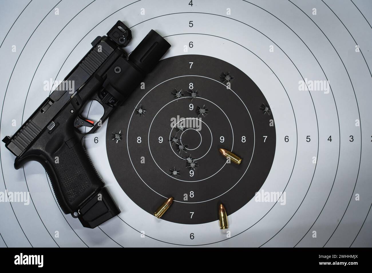 A shooting target with bullet holes in the center and a tactical pistol ...