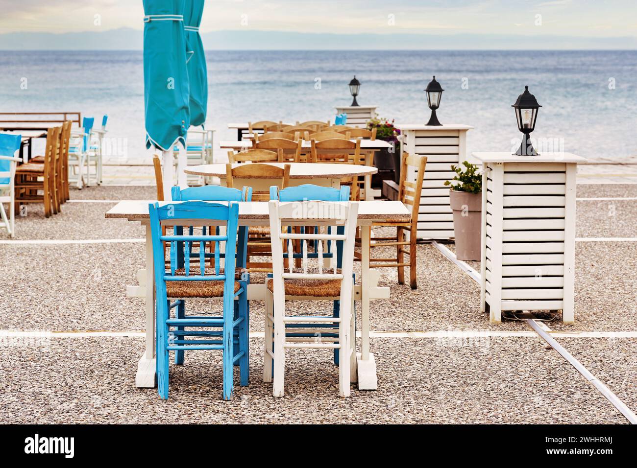 Wooden chairs and tables in blue and white in a taverna on the terrace next to the sea, tourist destination in Chalkidiki, Greec Stock Photo