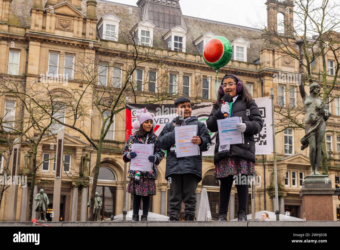 Leeds, UK. 10 FEB, 2024. Three young children read a story about the origins of the Watermelons links with Palestine out loud to the assembled crowd. Credit Milo Chandler/Alamy Live News Stock Photo