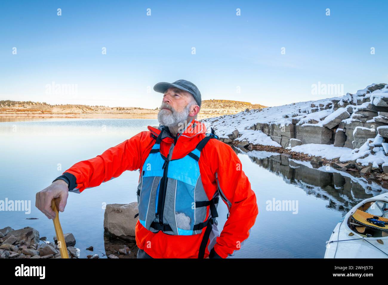senior canoe paddler wearing life jacket on a shore of Carter Lake in northern Colorado in winter scenery Stock Photo