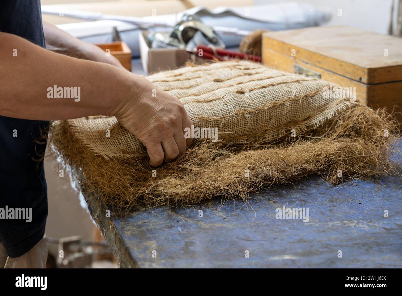 Upholstery craftsman shapes a pack filled with plant fibers like coir or palm fiber for a seat or sofa, traditional craft skill Stock Photo