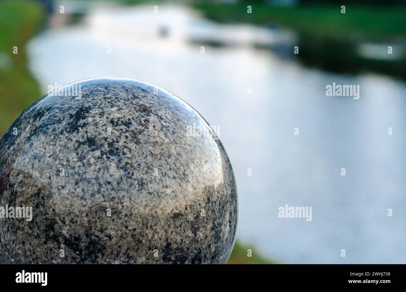 Large decorative marble ball against the background of the river in the evening Stock Photo