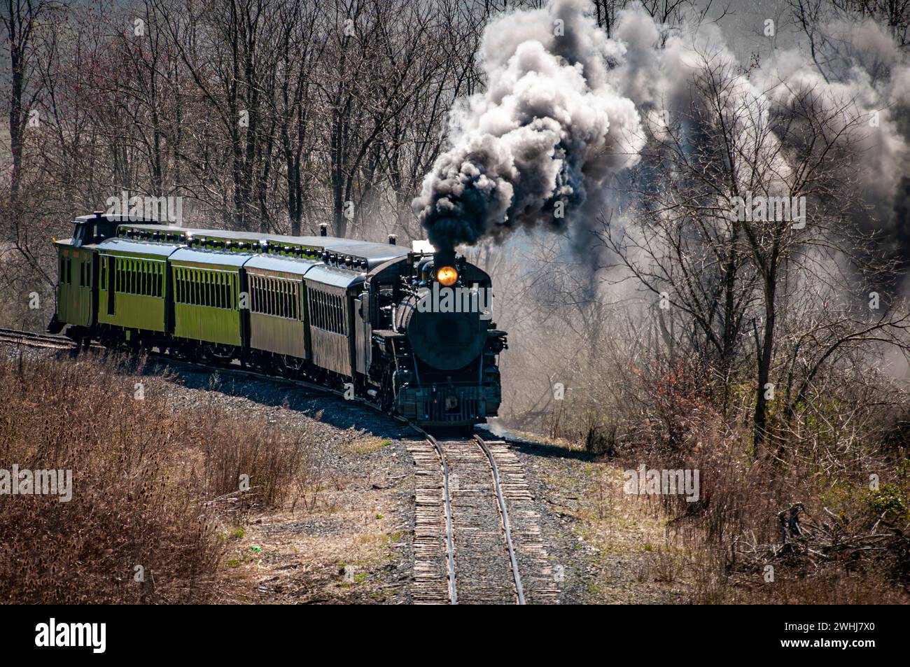Front and Slightly Above View of an Approaching Restored Narrow Gauge Passenger Steam Train Blowing Smoke Stock Photo