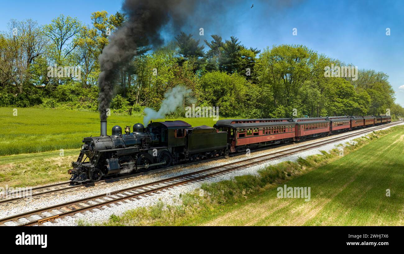 Aerial View from the Side of An Antique Steam Locomotive and Passenger Coach Stopped Blowing Smoke Stock Photo