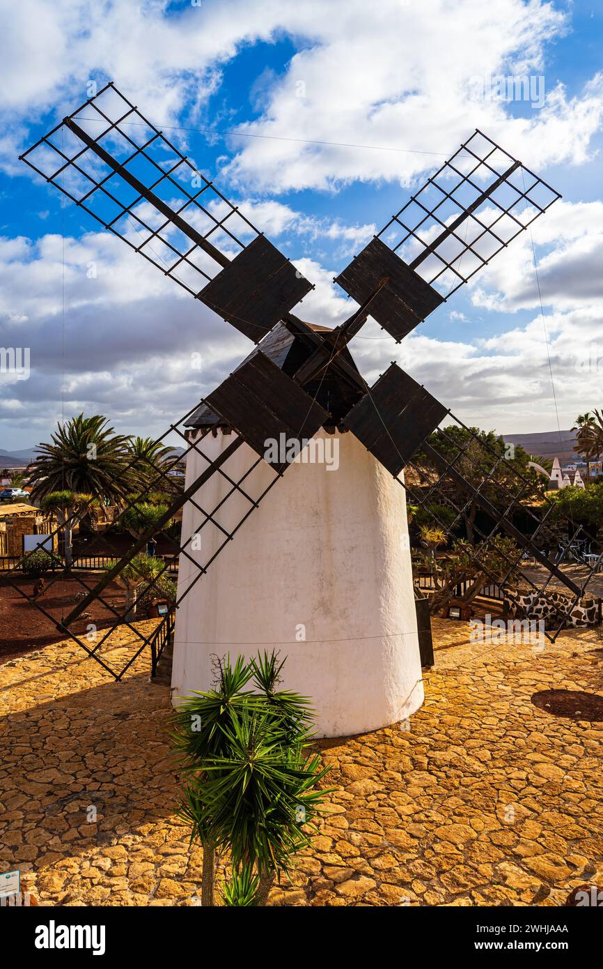 A traditional windmill amidst a scenic landscape, under a bright sky
