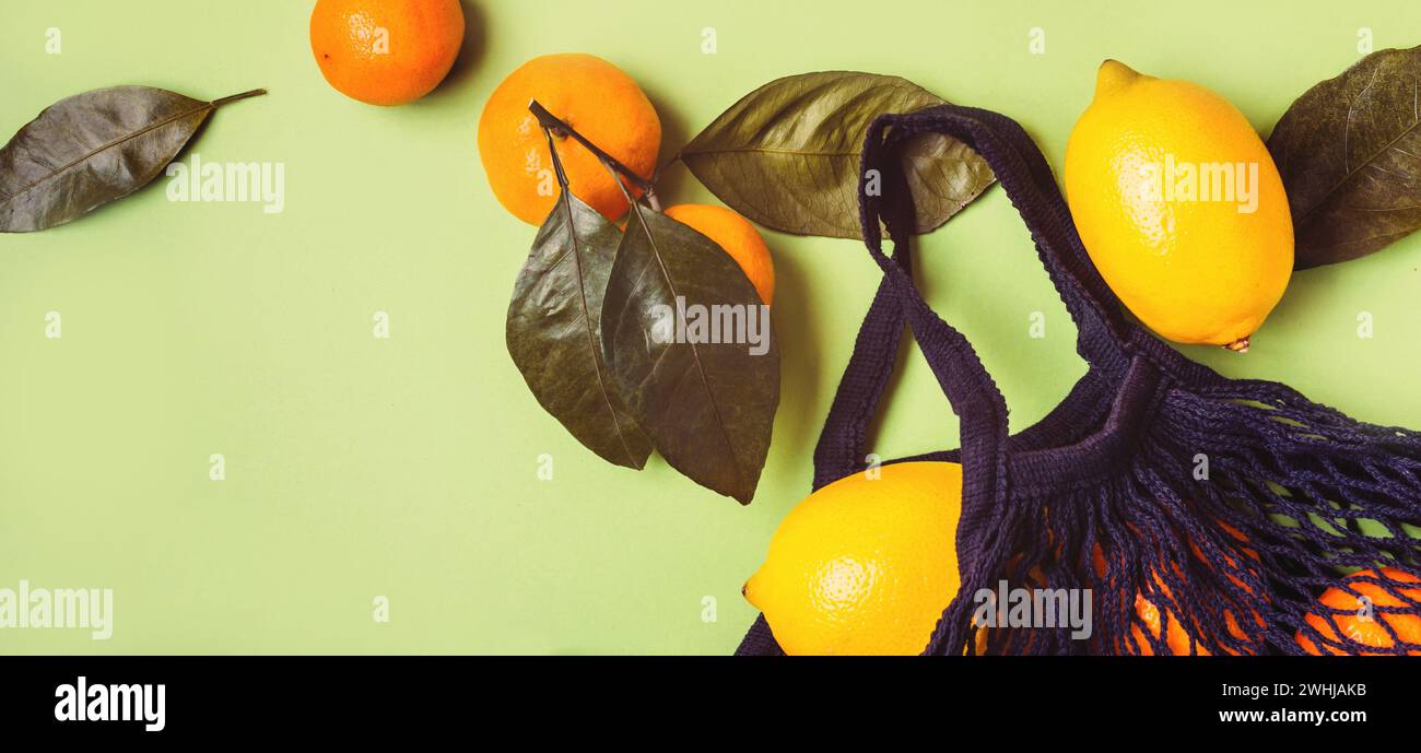 Set of citrus in mesh textile bag on green background Stock Photo