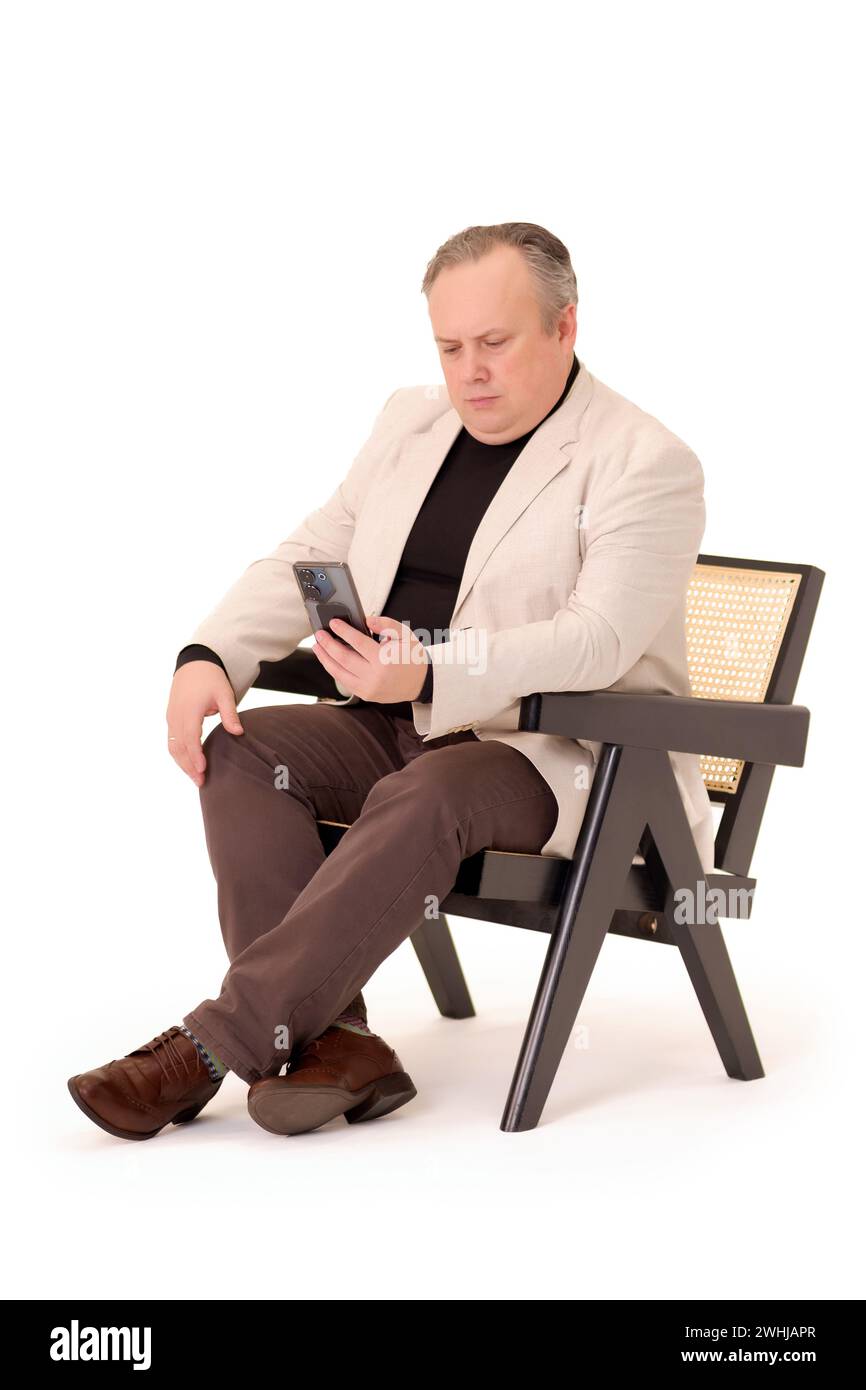 man in a chair watching something on his phone on a white background ...