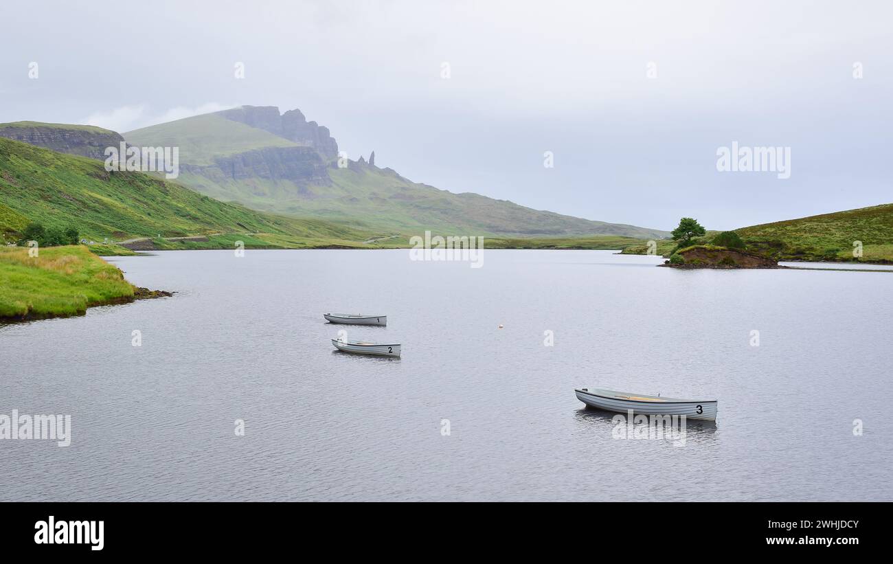 3 white fishing boats on Loch Leathan lake on a misty morning, Old Man of Storr rocks in the distance, Isle of Skye, Scotland, UK, Europe Stock Photo