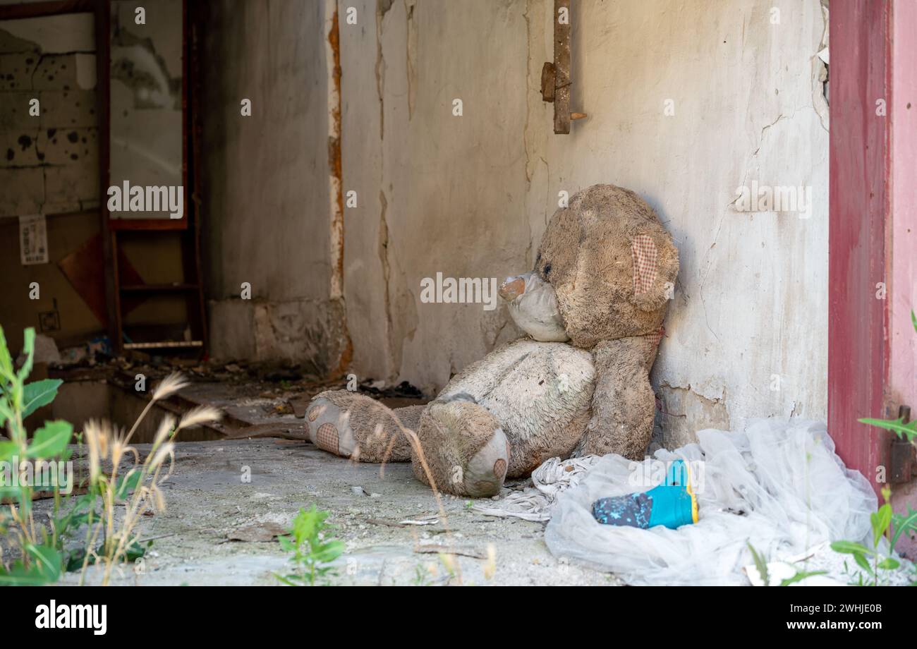 Bear children's soft toy near the wall of a destroyed house in Ukraine Stock Photo