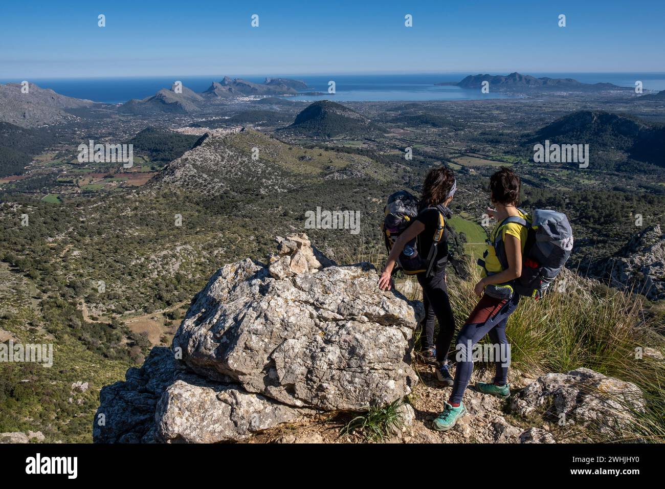 Hikers ascending Cucuia de Fartaritx with Alcudia bay in the background Stock Photo