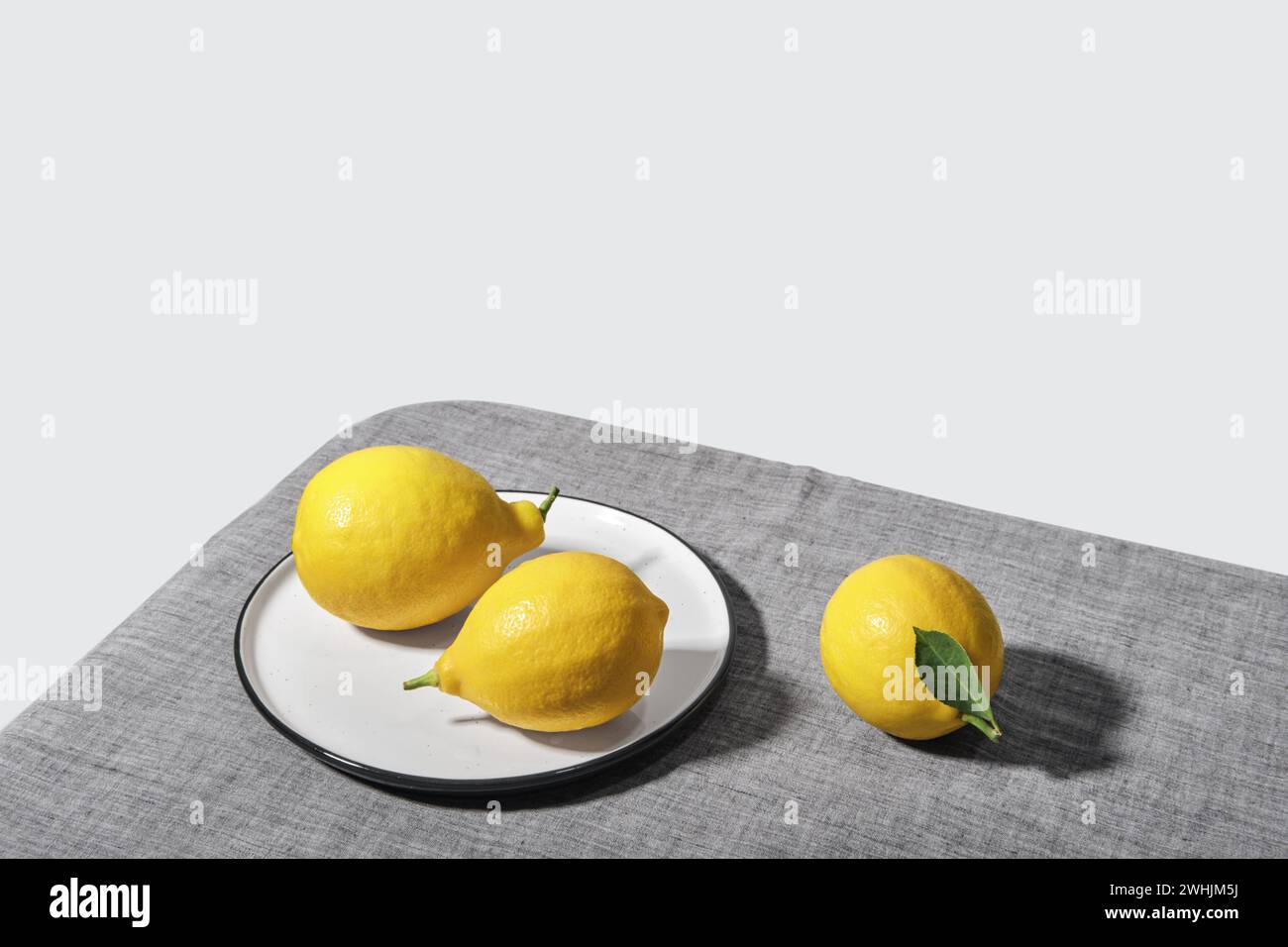 Trending colors of 2021. Yellow illuminating lemons on Ultimate gray tablecloth. Isometric view minimal still life Stock Photo