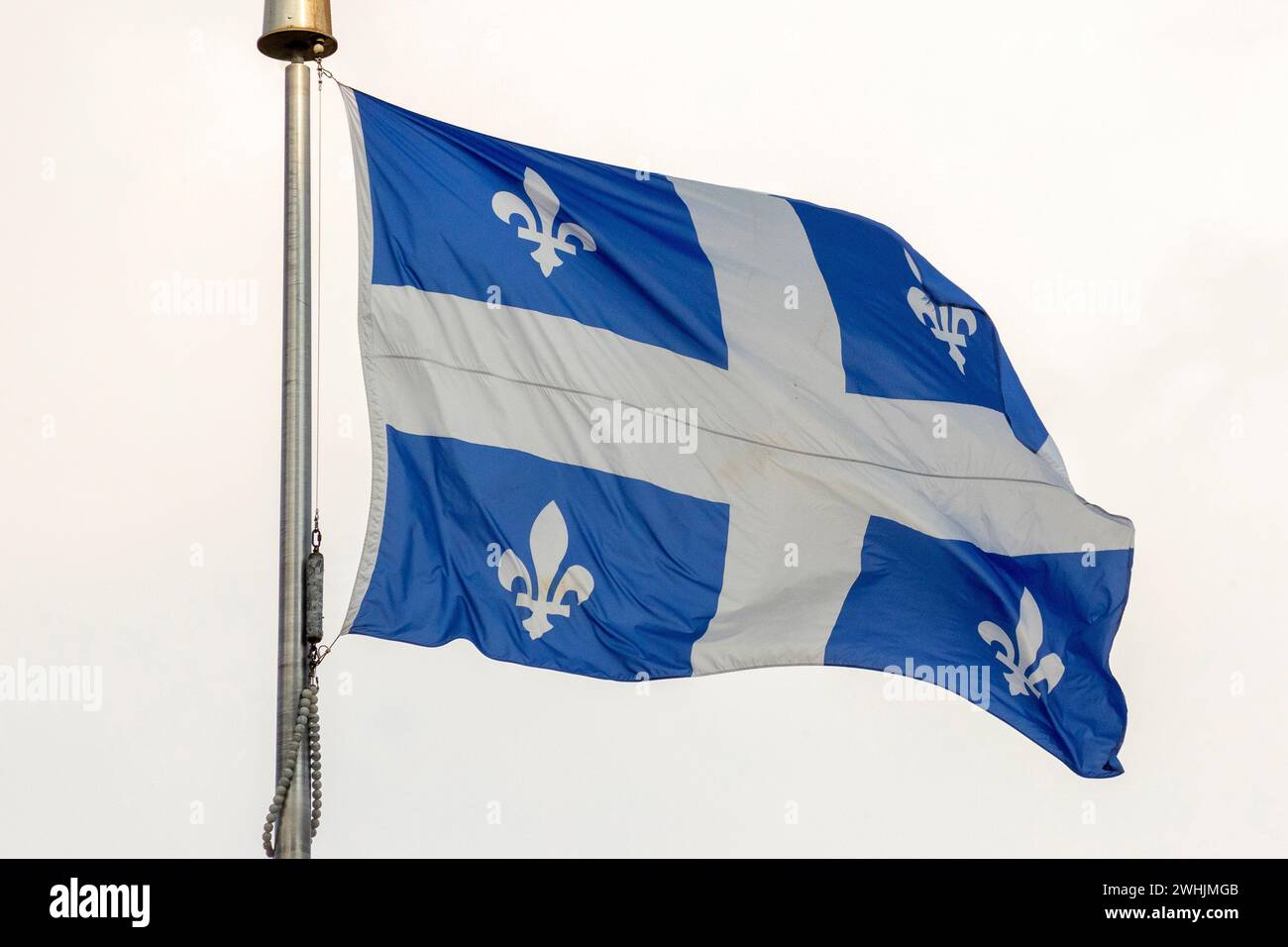 National flag of Quebec on a flagpole flutering on a wind Stock Photo