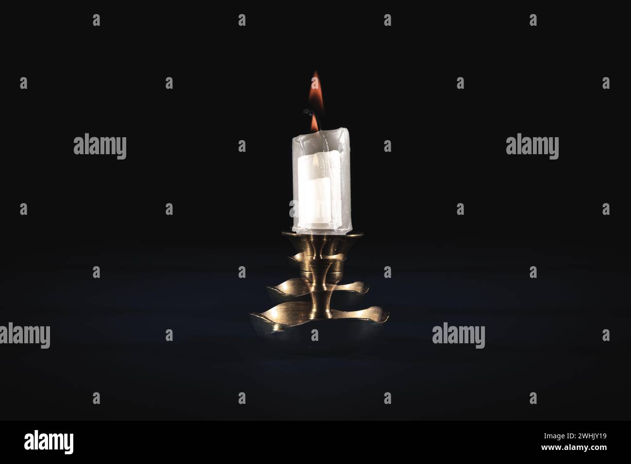 A double exposure of a single, glowing candle in the dark Stock Photo