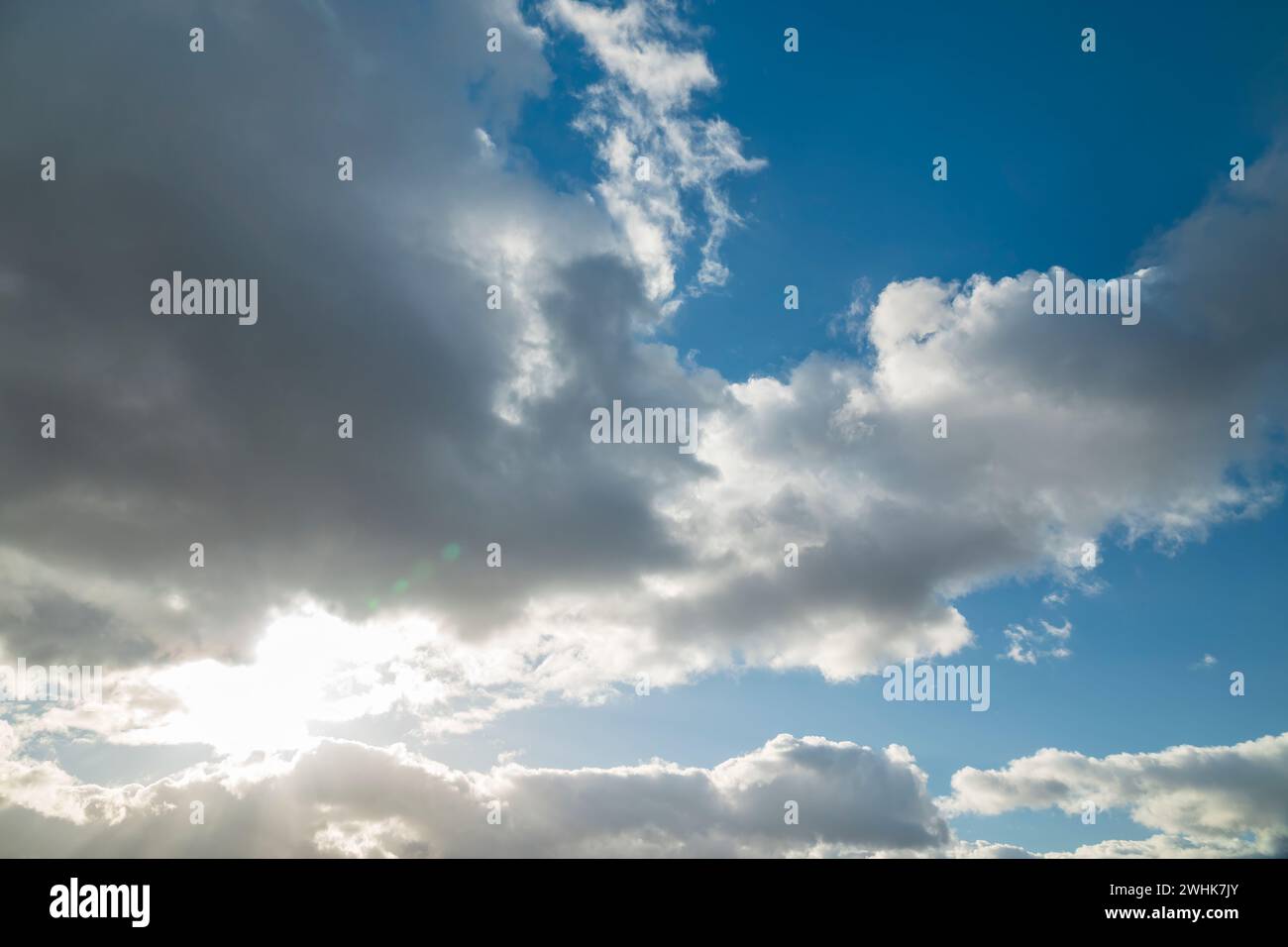 Blue sky background with sun shining through the clouds Stock Photo