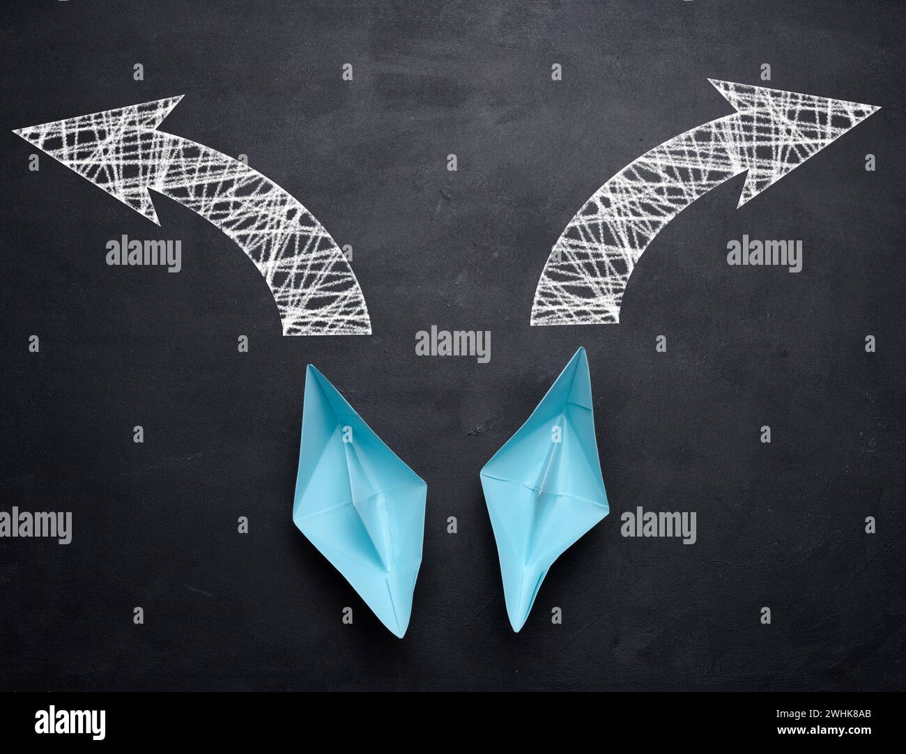 Two paper boats are moving in different directions on a black background, top view Stock Photo