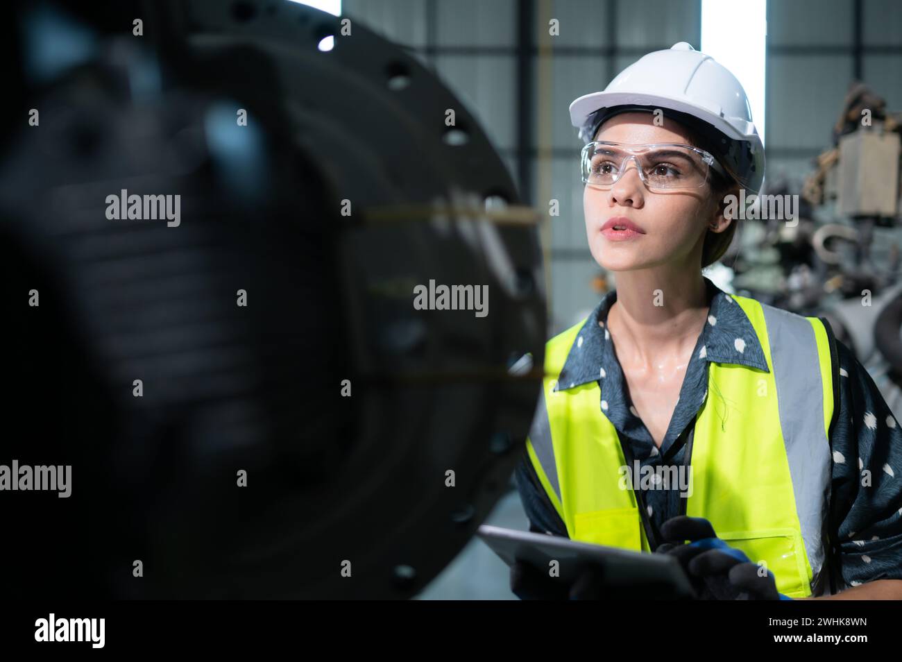 A female engineer installs a program on a robotics arm in a robot warehouse. And test the operation before sending the machine t Stock Photo