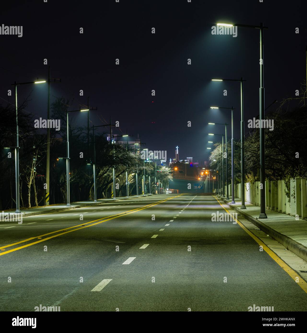 Night photo of empty four lane street illuminated by street lamps with ...