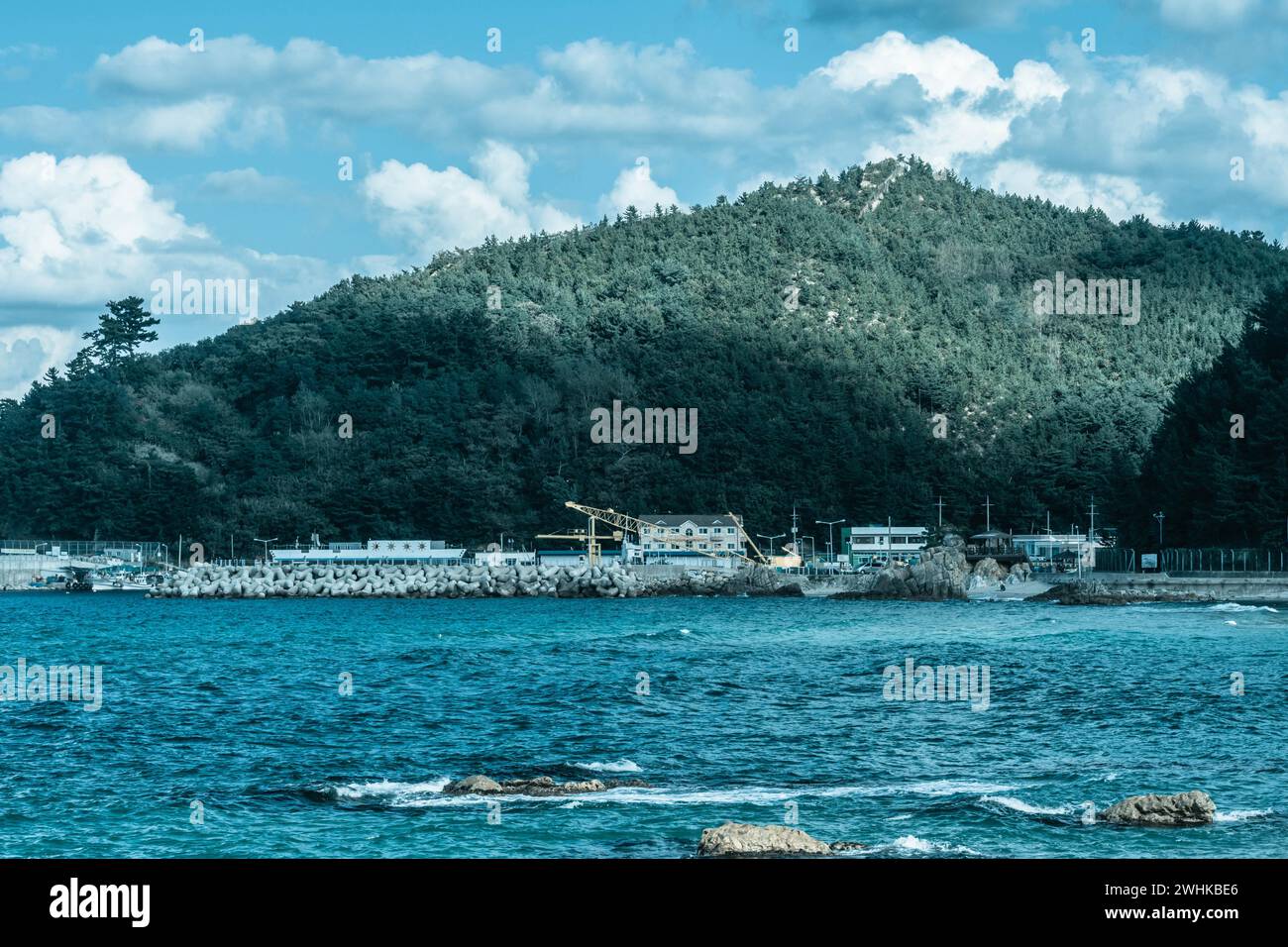 Landscape beautiful blue ocean and fishing port at foot of mountain under blue sky with puffy white clouds in South Korea Stock Photo